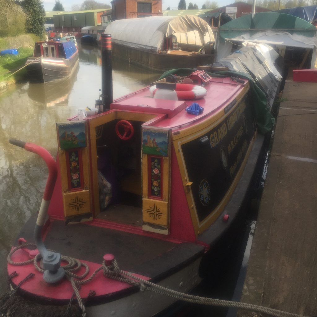 canal boat moored at boatyard with other boats.